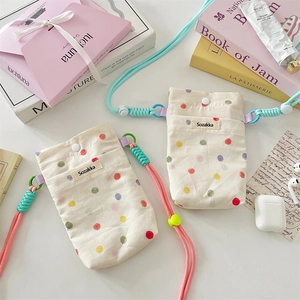 Close-up of canvas polka dot phone bags with colorful braided straps and woven label