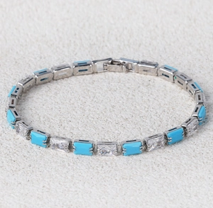 Detailed close-up of a silver chain bracelet with turquoise and clear zircon stones