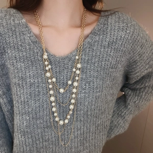Detail of elegant multilayer long necklace with white pearls on golden alloy chain