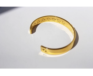Detailed view of gold plated minimalist open bangle with engraved star patterns inside