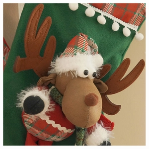 Detail of 3D reindeer plush ornament on a festive green and red Christmas stocking