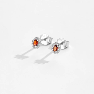 Close-up of S925 sterling silver stud earrings with red oval-cut zircon stone setting