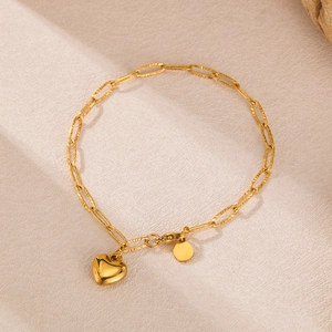 Gold paperclip chain bracelet featuring a polished heart pendant and a round metal tag
