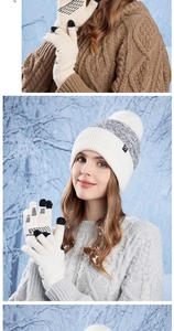 Close-up of winter knit hat with pompom and touch screen gloves in a snowy setting