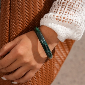 Détail du bracelet en résine à motif marbre vert au poignet pour un style de vacances