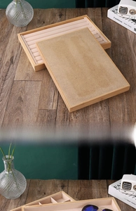 Detail of solid wood jewelry display tray with pink velvet slots for rings and necklaces
