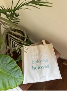Close-up of gradient beloved embroidery on durable cream white canvas tote bag