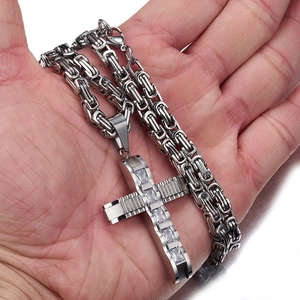 Makroaufnahme einer Byzantiner-Kette mit Zirkonia-Kreuzanhänger in der Hand