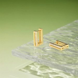 Close-up of gold rectangular hoop earrings with pavé-set white zircons on glass base