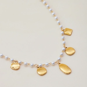 Détail du collier plaqué or 18 carats avec perles de verre blanches et pendentifs dorés