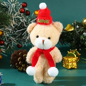 Cute beige plush bear with red knitted LOVE hat and scarf in a festive Christmas setting
