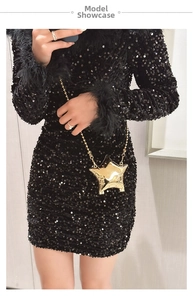 Detailed view of shiny gold star-shaped mini clutch bag with bead chain on model