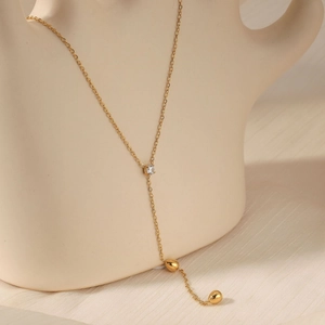 Elegant gold Y-shaped necklace with zircon and double teardrop pendants on silk backdrop