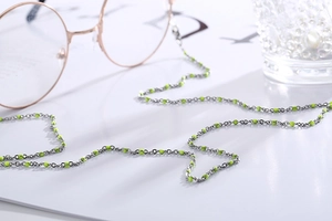 Detail of eyewear chain with silver links and neon green beads on magazine background