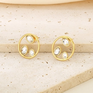 Macro shot of gold hollow circular stud earrings with three inlaid sparkling crystals