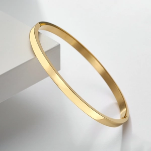 Minimalistischer goldener Edelstahl-Armreif mit polierter Spiegeloberfläche auf weißem Stand