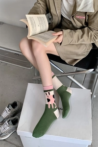 Detail of green cotton crew socks with pink cartoon rabbit patterns and color block cuffs