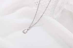 Vue détaillée du collier pendentif guitare argenté sur fond en soie blanche