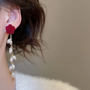 Detail of red rose studs with white pearl tassels on a model for a vintage look