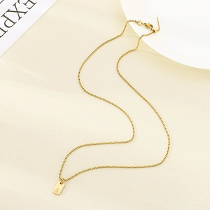 Detail of a gold box chain necklace featuring a square rectangular letter A pendant
