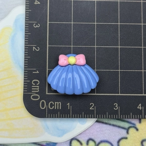 Macro shot of 2cm blue shell resin flatback with pink bow on a metric measurement grid