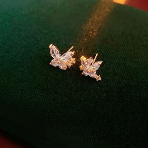 Exquisite gold-plated butterfly stud earrings set with sparkling zircons on green velvet