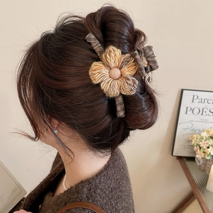 Detail of coffee knit flower hair claw clip with pearl center on model side profile