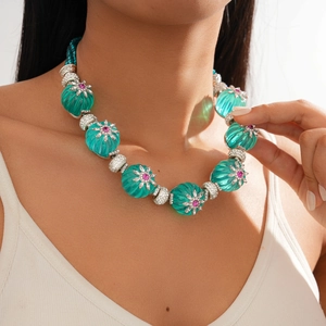 Close-up of green pumpkin beads necklace with pink flower gems and sparkling crystals