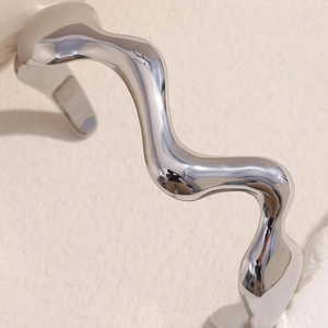 Macro detail of high-polish irregular wavy bangle with modern liquid metal mirror finish