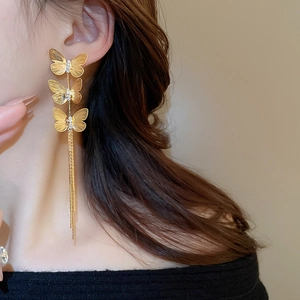 Detail of gold-plated butterfly tassel earrings with zircons shown on a model