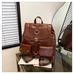 Detail of vintage brown leather backpack featuring silver buckles and two front pockets