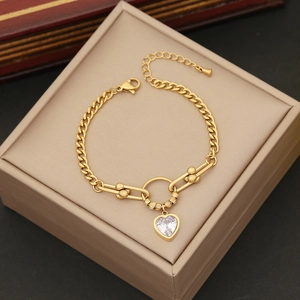 Detail of gold chain bracelet featuring a heart crystal pendant and lobster clasp closure