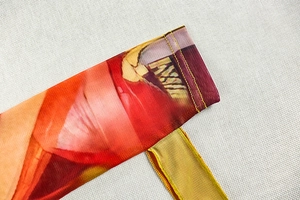 Detail of mesh fabric showing orange and purple gradient with yellow reinforced stitching