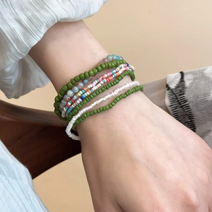 Close-up of bohemian multilayer beaded bracelets in green and white on a model wrist