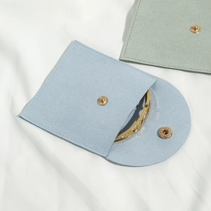 Macro view of microfiber jewelry pouch with curved snap closure and gold bracelet inside