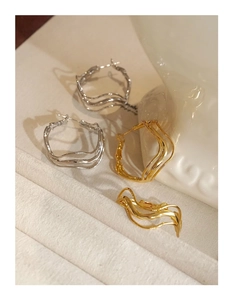 Detail of twisted gold and silver hoop earrings with irregular geometric wave layers