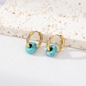 Close-up of golden stainless steel hoop earrings with turquoise natural stone beads