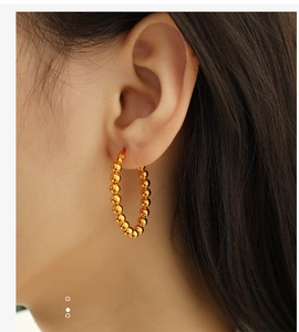Close-up of minimalist gold beaded hoop earrings worn by a model in an elegant style