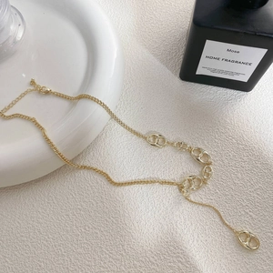Detalle de collar dorado con eslabones en forma de D sobre superficie blanca
