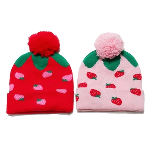 Kids strawberry knit beanie hats in red and pink with fluffy pom-poms on white background
