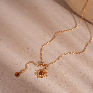 Macro detail of sunburst pendant with tiger eye stone and elegant gold bead chain
