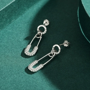 Silver S925 paperclip stud earrings with clear zircon stones on textured green background