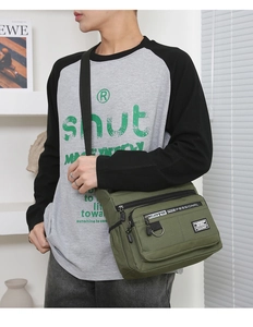 Detail view of army green canvas crossbody bag with multiple zippers and adjustable strap