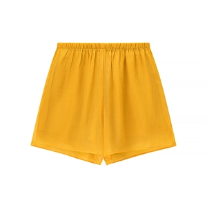 Detail of bright yellow high-waisted shorts featuring elastic waistband and wide-leg cut
