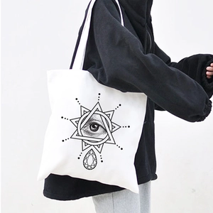 Detail of white canvas tote bag with black Egyptian Demon Eye and geometric print
