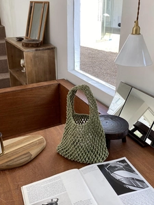 Detail of green woven cotton rope tote bag with mesh pattern on a wooden table