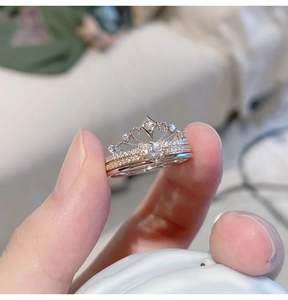 Detail of crown combination rings in silver and rose gold held by hand showing fine zircon