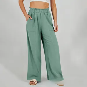 Dettaglio dei pantaloni larghi in lino verde salvia con elastico in vita e grandi tasche applicate