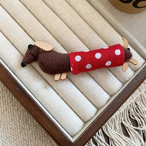 Detailed macro view of a fabric dachshund hair clip with red polka dot vest on beige velvet