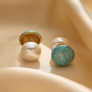 Macro view of double-sided gold-plated earrings with white pearl and green marble studs